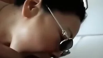 Asian girl with sunglasses sucks cock, while getting fingered.